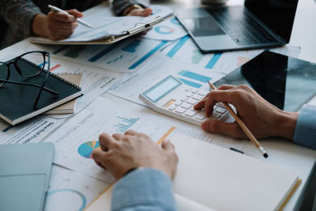 Two business colleague meeting to brainstorm the new project business strategy plan and analysis data document, finance and accounting concept. close up hand using calculatorの写真素材