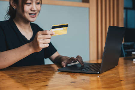 Close up of asian girl hold bank credit card and type on laptop, shopping online using computer,...