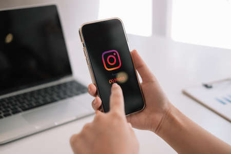 CHIANG MAI, THAILAND - MAR 06 2022: A woman holds Apple iPhone 13 with Instagram application from...