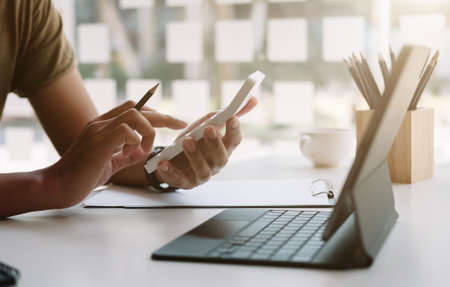 Close up of businessman or accountant hand holding pen working on calculator to calculate business...
