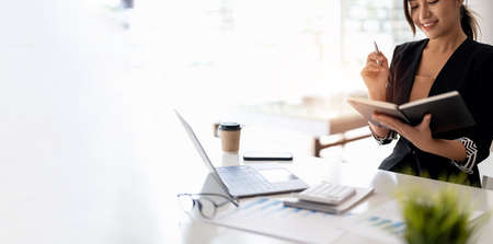Closes up accountant asian woman hand is writing on notepad with pen in office. business accounting concept.の写真素材