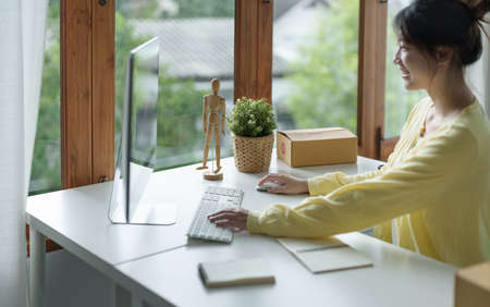 Smiling young freelance businesswoman using desktop pc in the office.の写真素材