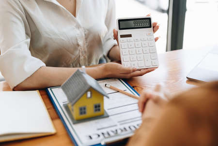 Real estate agent or bank officer describes the loan interest to the customer with home purchase contracts or on office loans and interest rates.の写真素材