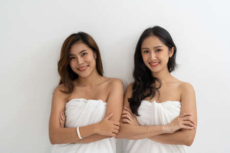 Portrait of Smiling young LGBT lesbian couple wearing a white towel standing and hugging each other affectionately together.の写真素材