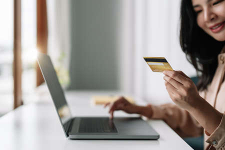 Close up of asian girl hold bank credit card and type on laptop, shopping online using computer, buying goods or ordering online, entering bank accounts and details in online banking offer.の写真素材