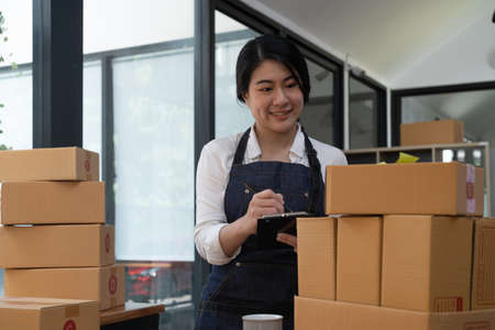 Asian young woman working with a box at home the workplace. start-up small business owner, small business entrepreneur SME or freelance business online and delivery concept.の写真素材