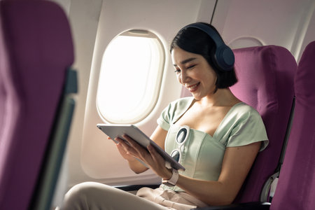 Passenger using tablet computer in airplane cabin during flight. watching series.の写真素材