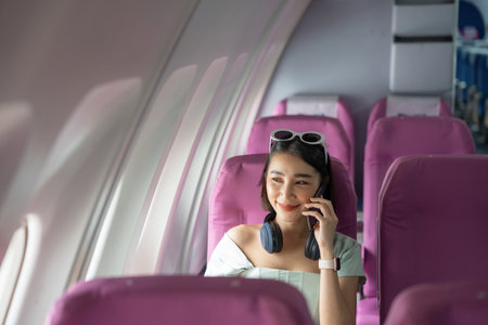 Attractive asian woman passenger of airplane calling mobile phone on board. tourism traveler...