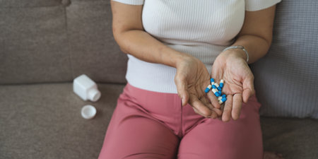 Elderly sick ill woman hold pills on hand pouring capsules from medication bottle take painkiller supplement medicine, old senior people pharmaceutical healthcare treatment concept, close up viewの写真素材