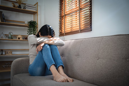 Young lonely attractive asian woman crying on couch feeling sad tired and worried suffering depression isolated at home. Mental Health and lockdown, stress, unemployment and heartbroken concept.の写真素材