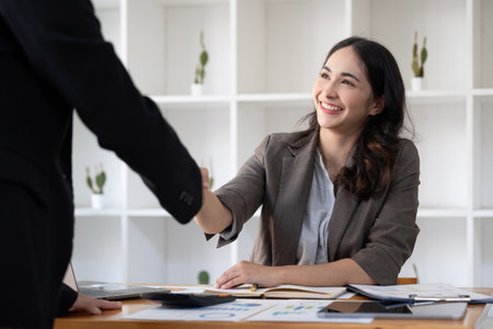 Smiling young businesswoman shaking hands with an office colleagueの写真素材