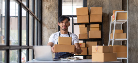 Young start up small business owner writing address on cardboard box at workplace.small business entrepreneur SME , working with box at home, Online selling, e-commerce, packing conceptの写真素材