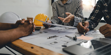 Architect and engineer team working with blueprints for architectural plan, engineer sketching a construction project, green energy conceptの写真素材