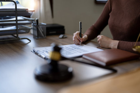 Close up business female hands holding pen, signing in white paper form or application to confirm and deal contract agreement on tableの写真素材