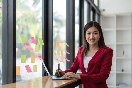 businesswoman work with laptop, writing notes on colorful sticky papers in officeの写真素材