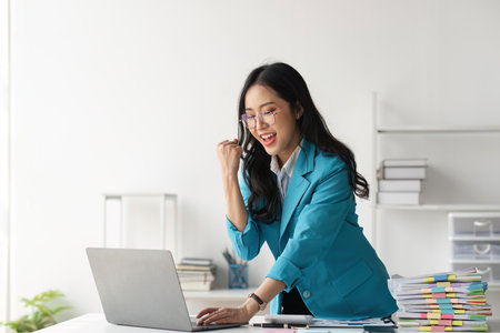 Young happy business woman worker or feeling excited winning online looking at laptop celebrating professional achievement, getting hired or approved at workの写真素材