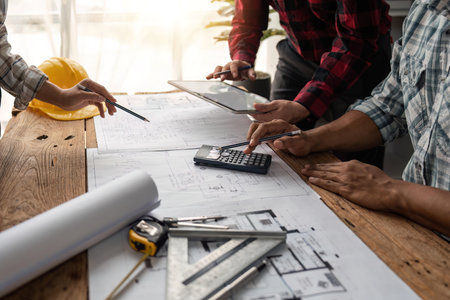 team engineer checks construction blueprints on new project with engineering tools at desk in officeの写真素材