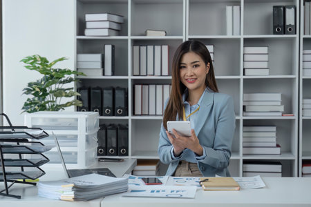 Businesswoman sits at work with laptop and computer and analyzes corporate and tax activities at officeの写真素材