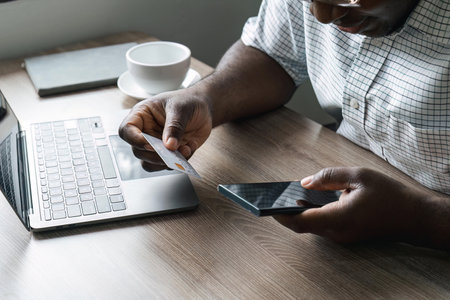 Man hand holding credit card and using mobile phone at home, Businessman or entrepreneur working, Online shopping, e-commerce, internet banking, spending money, working from home conceptの写真素材