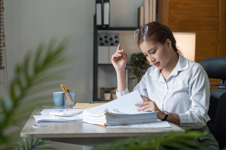 business female workers holding are arranging documents of unfinished documents on office desk,...