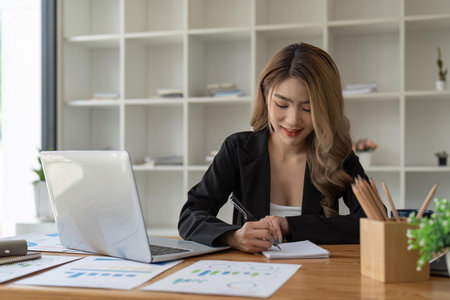 Business woman hand working at a computer and writing on a notepad. business financial conceptの写真素材
