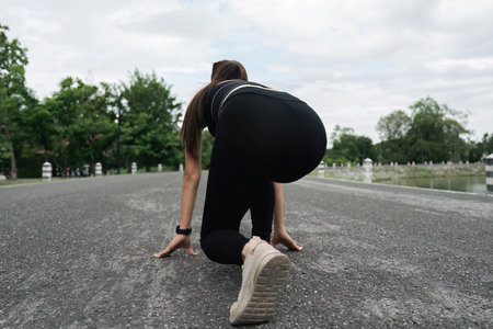 Sportive woman outdoors. Young lady doing exercises and ready to start running. Health and sport conceptの写真素材