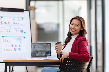 Beautiful female employee sitting in office in coffee mug handheld. After presentation from meeting