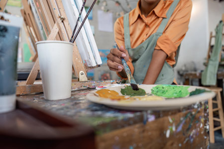 Hands of female artist artist with palette painting at art studioの写真素材