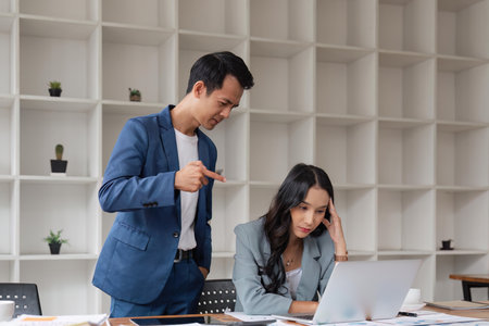 Two business people being stressed while working on a laptop in an office, Business partners working together, Collaborating teamwork analyzing paperwork data, business reportsの写真素材