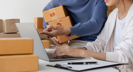 Happy couple people packing parcel boxes, couple lover checking order online on laptop at home