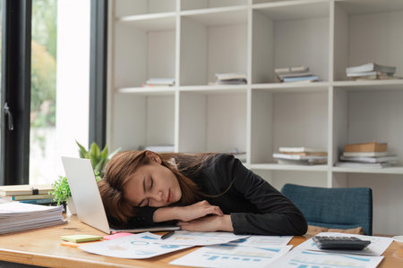 Tired frustrated and overworked business woman sleeping on the laptop in the officeの写真素材