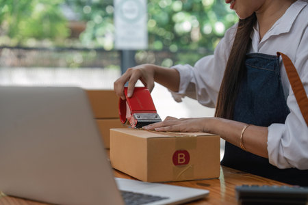 Asian owner business woman work at home for online shopping sale and packing products to deliver to customersの写真素材