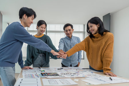 business team of developers or graphic designers putting their hands together at working table in officeの写真素材