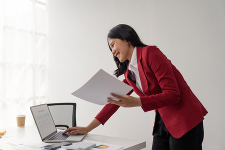 Portrait of beautiful smiling young businesswoman sitting at work and typing on screen laptopの写真素材