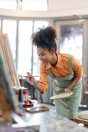 african american female artist painting on canvas doing some art projects on her studio workshop
