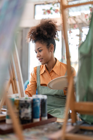 An African American woman who loves art or a female artist is holding a paint palette and...