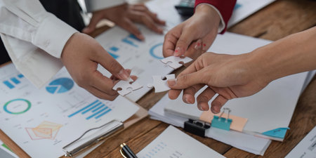 Concept of teamwork and partnership. Hands join puzzle pieces in the office. business people putting...
