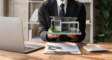 A real estate agent holding a small new house in her handsの写真素材