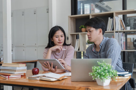 Education, teaching, learning, technology and people concept. Two Asian male and female students...
