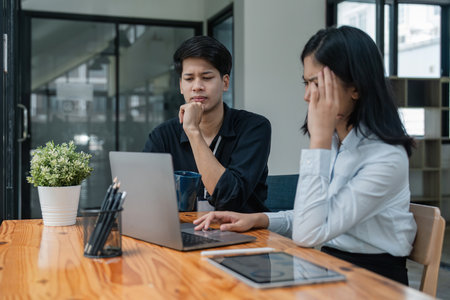 Two Asian business feeling migraine head strain. Overworked businesswoman financier while working on laptop and tablet at officeの写真素材