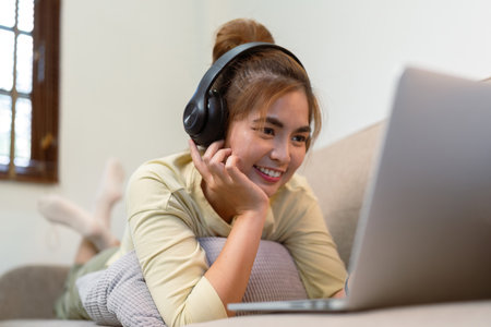 Concept of relaxation at home, Happy Asian woman watching online movie via laptop in living room