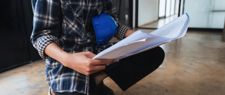 Electrical engineers analyze work from blueprints for wiring setupの写真素材