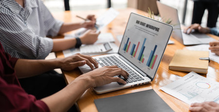 Business team analyzes financial business finance reports on laptop and graph documents during corporate meeting discussions showing successful teamwork, business meeting ideasの写真素材