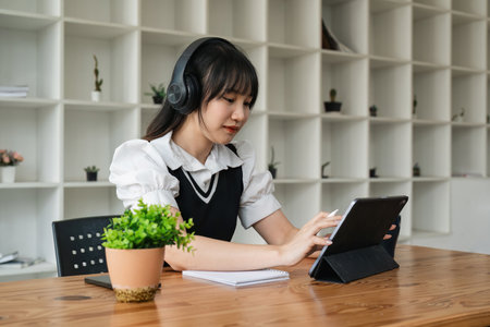 Online learning. Cheerful school studentgirl studying using digital tablet and wireless headphones...