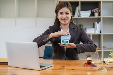 Confident asian female lawyer home protection working in office with reading contract documents sitting at desk. Law services, advice, justice and real estate conceptの写真素材
