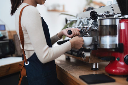 Asian female barista checking equipment inside shopの写真素材