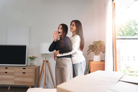 Homosexual happy young Asian woman hug girlfriend after moving stuff to a new rent houseの写真素材