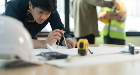 Close up engineer man working of sketching a construction project on his project at officeの写真素材