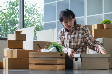 Young asian man smiling confident unpacking cardboard box at new homeの写真素材