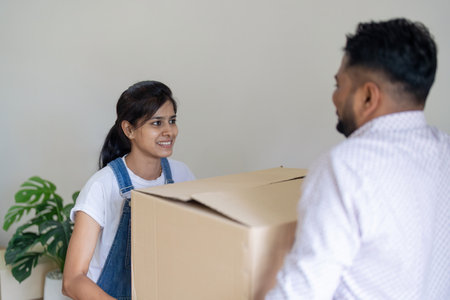 Happy excited beautiful indian young couple move the box into the home at new home. Relocation,...